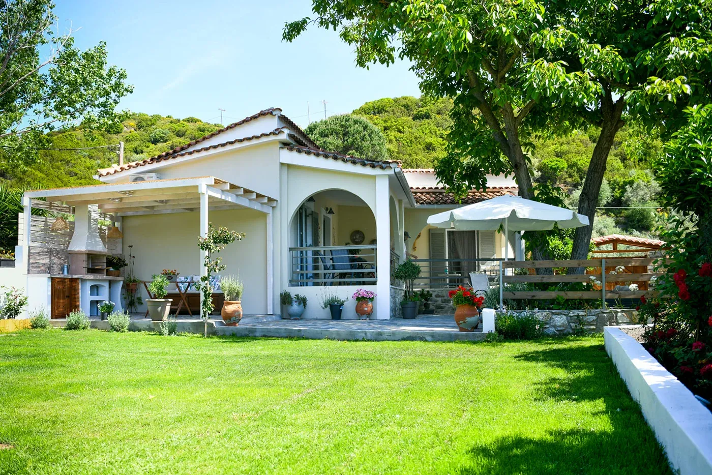 The house across the lawn, with the green hills behind
