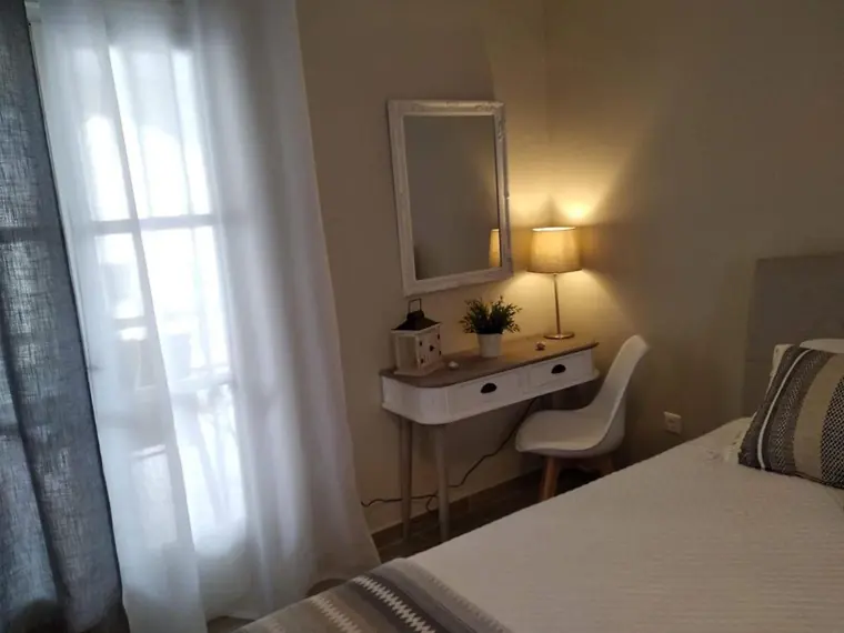 A desk and mirror by the bedroom window