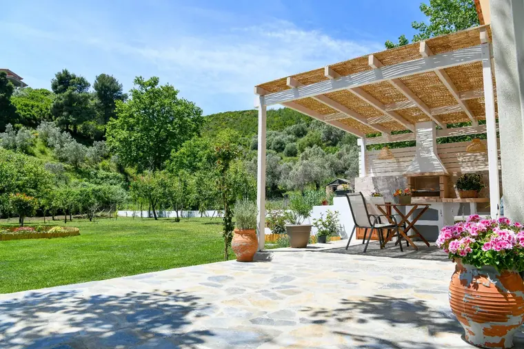 The pergola with its built-in barbecue beside the lawn